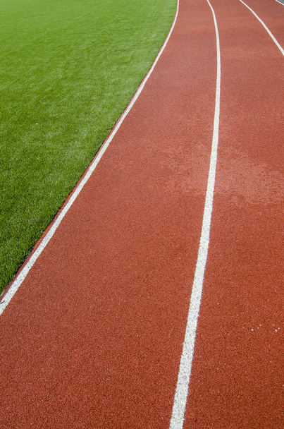 The running track rubber lanes in the artificial grass stadium. - Foto, Bild
