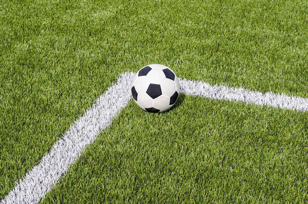 The soccer football on the white line in the artificial green grass field - Photo, image