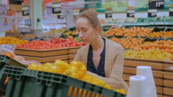 Woman buying fresh orange bell peppers at grocery store - Footage, Video
