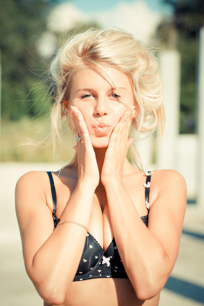 Young beautiful blond woman touching cheeks and put lips in kiss - Фото, зображення