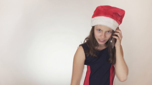 Kaunis tuhma tyttö teini-ikäinen joulupukki hattu emotionaalisesti kommunikoi älypuhelimella valkoisella taustalla varastossa video
. - Materiaali, video