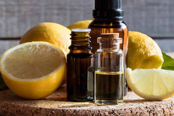 Bottles of lemon essential oil with lemons - 写真・画像