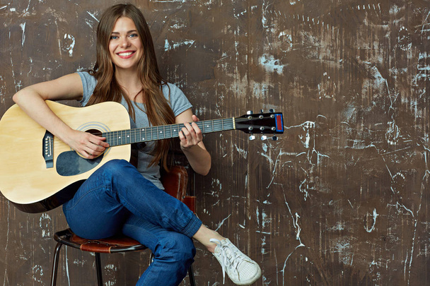 Smiling woman sitting and playing guitar - Fotó, kép