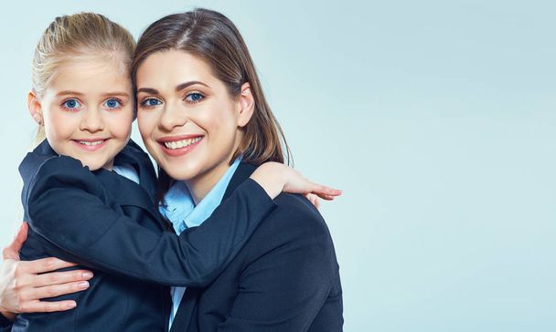 little girl hugging with smiling businesswoman on blue background - Foto, Imagen