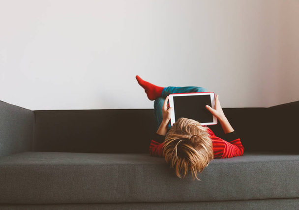 маленький мальчик читает электронную книгу расслабленной дома
 - Фото, изображение