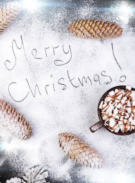 Merry Christmas Handmade Text on Snow. Christmas Food Sweet Marshmallow with Chocolate in Brown Cup on Black Background. Flat Lay.  - Photo, Image