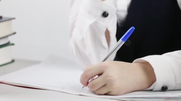 Schoolgirl writing in exercise book at table, close up, tilt - Video, Çekim