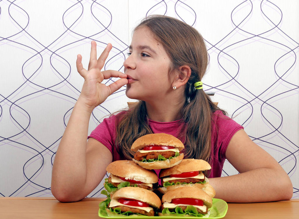 счастливая маленькая девочка с гамбургерами и лакомым кусочком
 - Фото, изображение