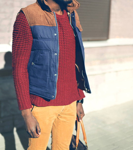 Fashion man in a red knitted sweater, vest jacket stands in the  - Foto, imagen