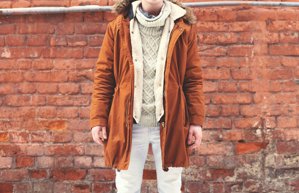 Fashion man in warm brown jacket posing on a textured brick wall - Фото, зображення