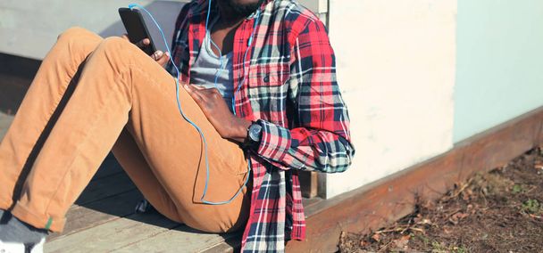 Fashion man listens to music on the smartphone sitting in the ci - Zdjęcie, obraz