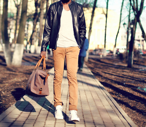 Fashion man model wearing a black leather jacket with bag in han - Φωτογραφία, εικόνα