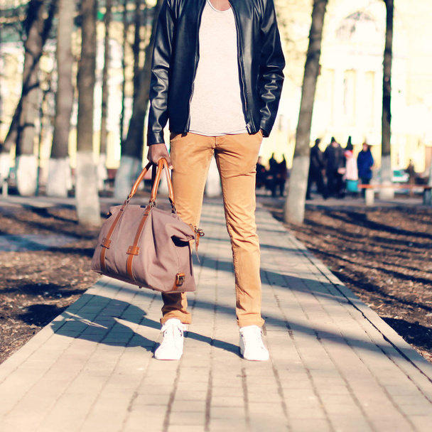 Fashion man stands with a bag in his hand outdoors close-up - Foto, imagen
