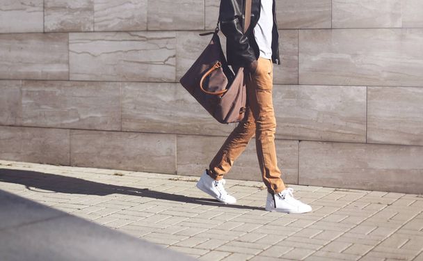 Fashion man wearing black leather jacket with bag walking at eve - Fotografie, Obrázek
