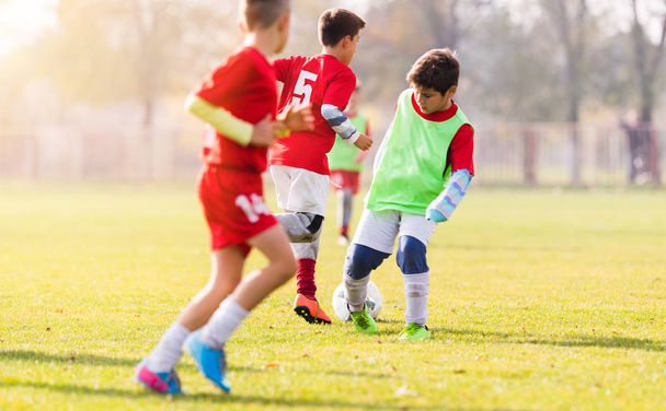 Chico pateando fútbol en el campo de deportes
 - Foto, Imagen
