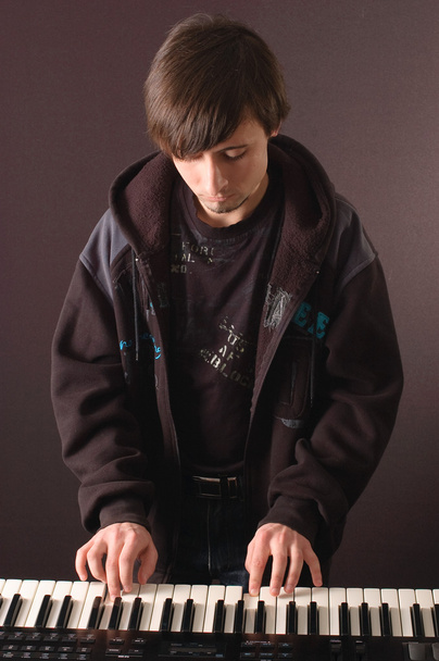 ένας νεαρός άνδρας που παίζουν σε ένα συνθεσάιζερ - Φωτογραφία, εικόνα