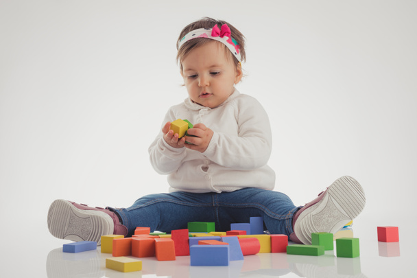 白い背景に分離された木製のキューブを弾いているかわいい赤ちゃん女の子 - 写真・画像