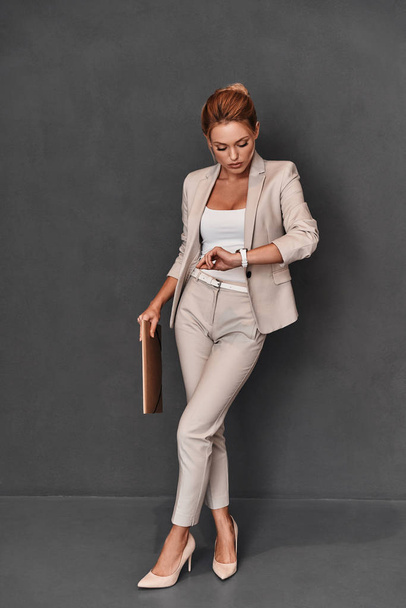 woman in suit holding brown folder - Foto, afbeelding