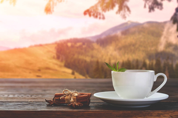 Tasse mit Tee auf dem Tisch über Berglandschaft mit Sonnenlicht. Schönheit Natur Hintergrund - Foto, Bild