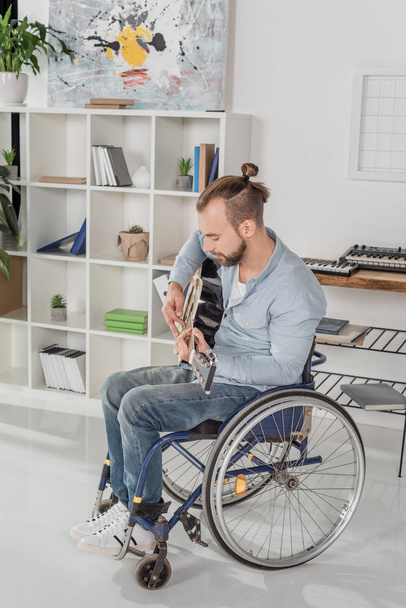 hombre en silla de ruedas tocando la guitarra
 - Foto, Imagen