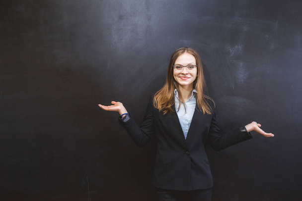 happy successful girl with glasses and in a suit posing by a dark wall - Фото, зображення