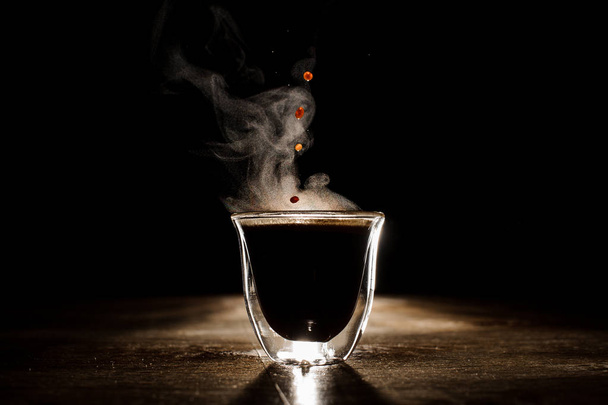 Hot coffee drink with steam spilling from clear glass coffee cup - Fotó, kép