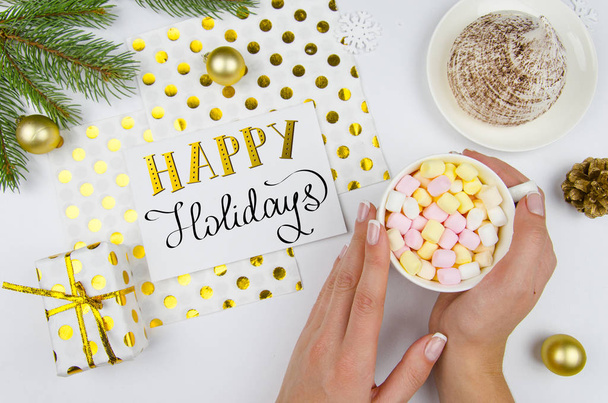 Neşeli Noel tebrik kartı. Çam dalları, hediye kutusu ve altın top ile beyaz tabloda marshmallow ile bir fincan tutan kadın. Mutlu tatiller diliyorum. Düz yatıyordu, en iyi görünümü - Fotoğraf, Görsel
