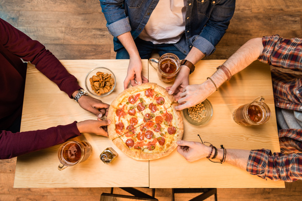 Männer trinken Bier und essen Pizza    - Foto, Bild
