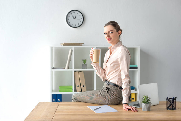 Бізнес-леді сидить на столі з кавою
 - Фото, зображення