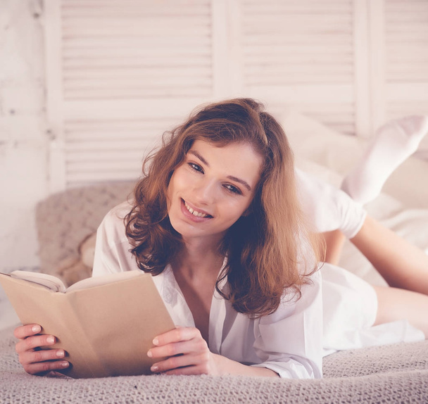beautiful blond woman reading book in the bed. Relaxing concept - Photo, Image
