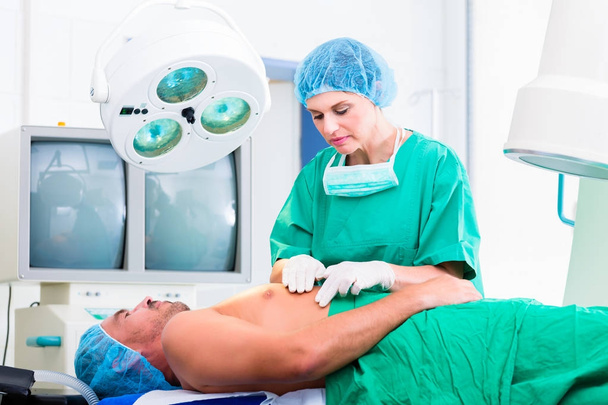 Ortopedinen kirurgi leikkaa potilaan
 - Valokuva, kuva