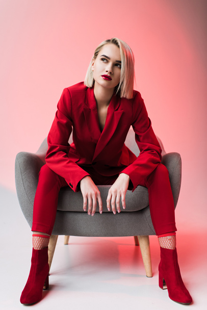 Nainen punaisissa vaatteissa poseeraa nojatuolissa
 - Valokuva, kuva