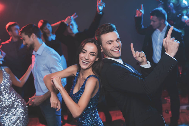 People have fun at the New Year's party. In the foreground, a guy and a girl are dancing. - Φωτογραφία, εικόνα
