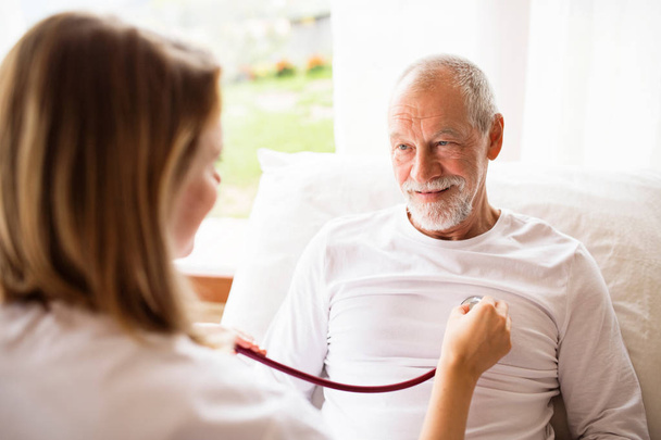 Health visitor and a senior man during home visit. - Fotó, kép