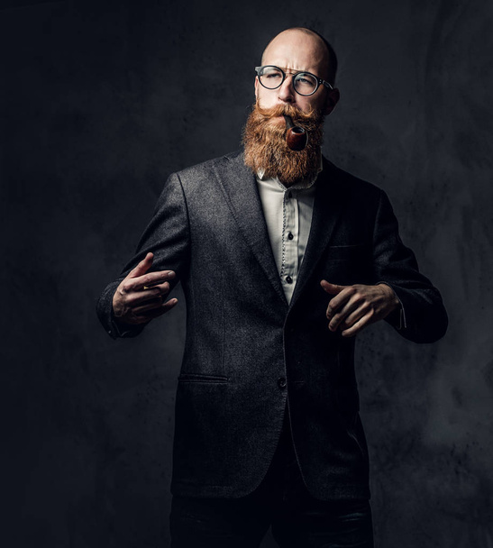 Studio portrait of redhead bearded male in vintage eyeglasses dressed in a wool jacket. - Photo, Image