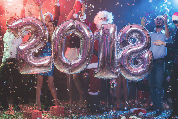 Os jovens na festa de Ano Novo estão posando com grandes bolas infláveis brilhantes na forma de números 2018
. - Foto, Imagem