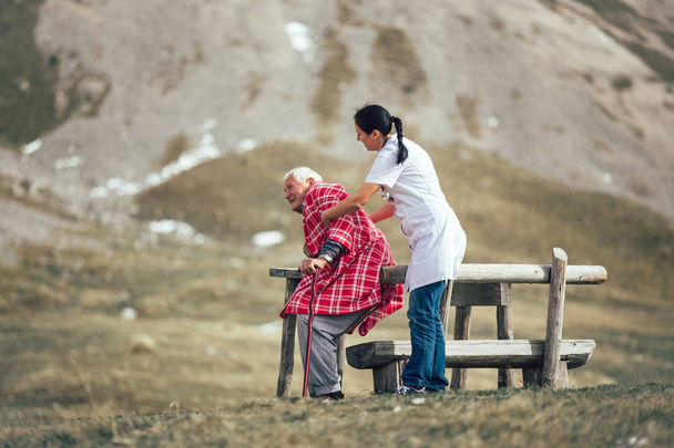 Медсестра помогает старшему мужчине идти
  - Фото, изображение