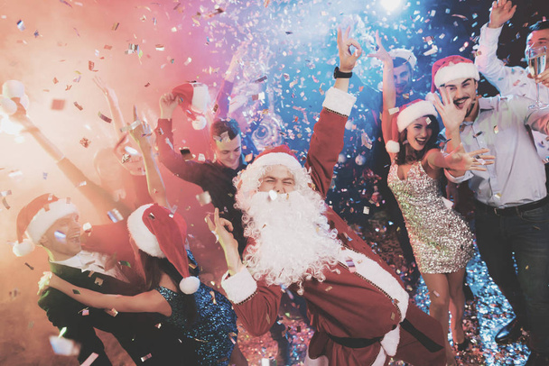 A man dressed as Santa Claus has fun at a New Year party. Together with him have fun friends. - Fotoğraf, Görsel
