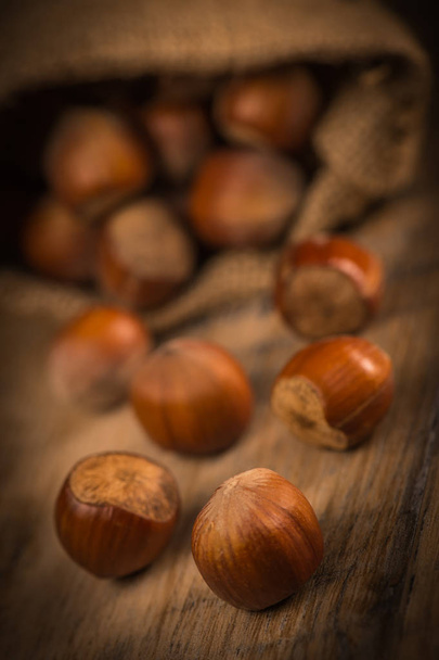 Hazelnuts and jute bag on rustic wooden background - Valokuva, kuva