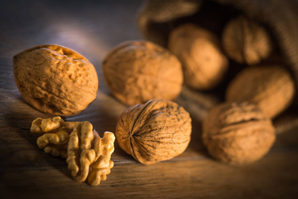 Walnut kernels and whole walnuts on rustic old oak table - Fotografie, Obrázek