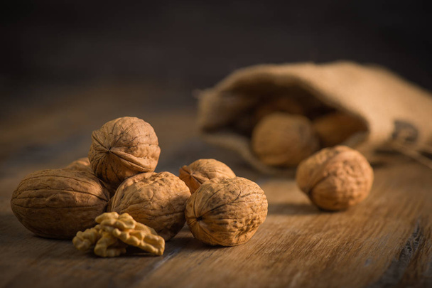 Walnut kernels and whole walnuts on rustic old oak table - Foto, Imagen