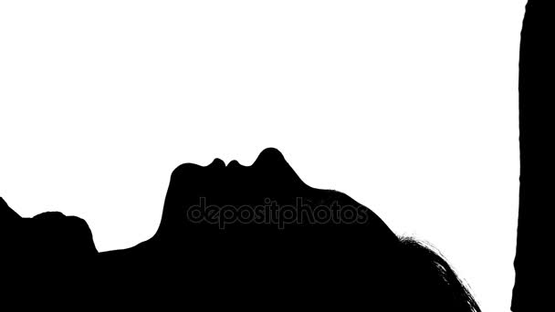 Meisje ligt op bed met haar zoenen kerel. Silhouet. Witte achtergrond - Video