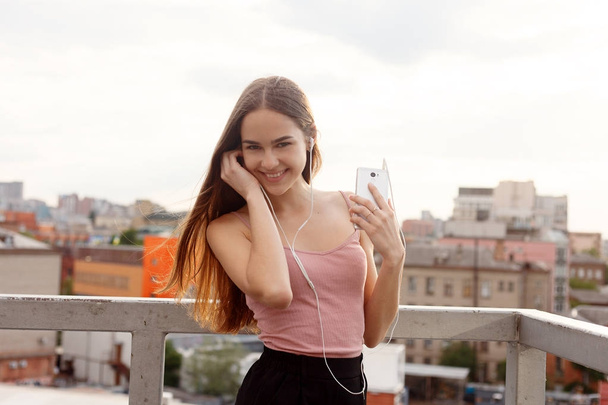 Young woman with headphones dangling on her mobile phone - Фото, зображення