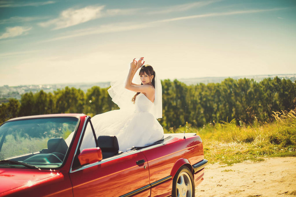 Runaway bride. Beautiful woman on red cabriolet - Foto, afbeelding
