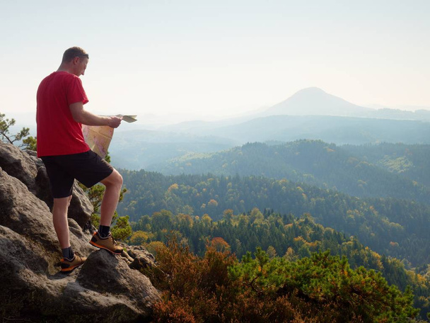 Sportieve figuur man stand op de berg met kaart. Toeristische reizen te voet, - Foto, afbeelding