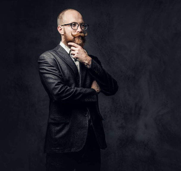 An elegant redhead bearded aristocratic male dressed in a suit and eyeglasses over grey background. - Photo, Image