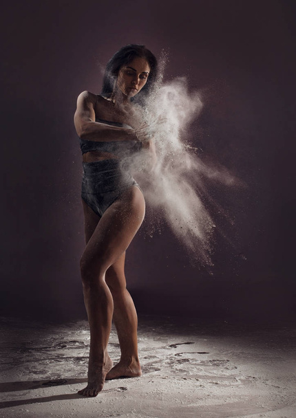 Contemporary dancer performing in cloud of powder - 写真・画像