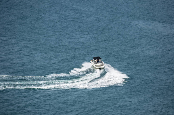 Моторний човен з туристами робить зигзаг на морі і залишає сліди хвиль і піни. Концепція в стилі: Життя було успіхом і розкішною відпусткою
. - Фото, зображення