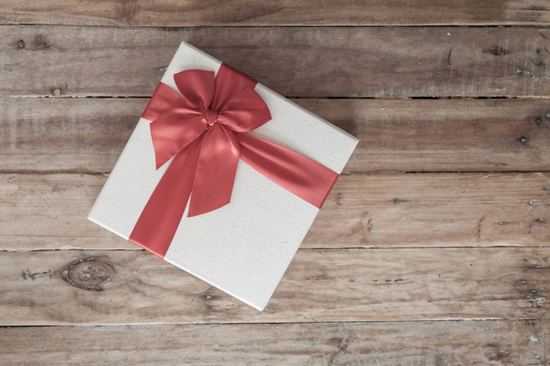 Coffret cadeau blanc et ruban rouge et mini coeur à l'intérieur sur fond bois
 - Photo, image