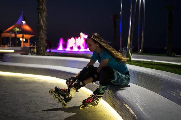 白人の女の子はボケ味でライトと夜の街でローラー_スケートを楽しんでいます - 写真・画像